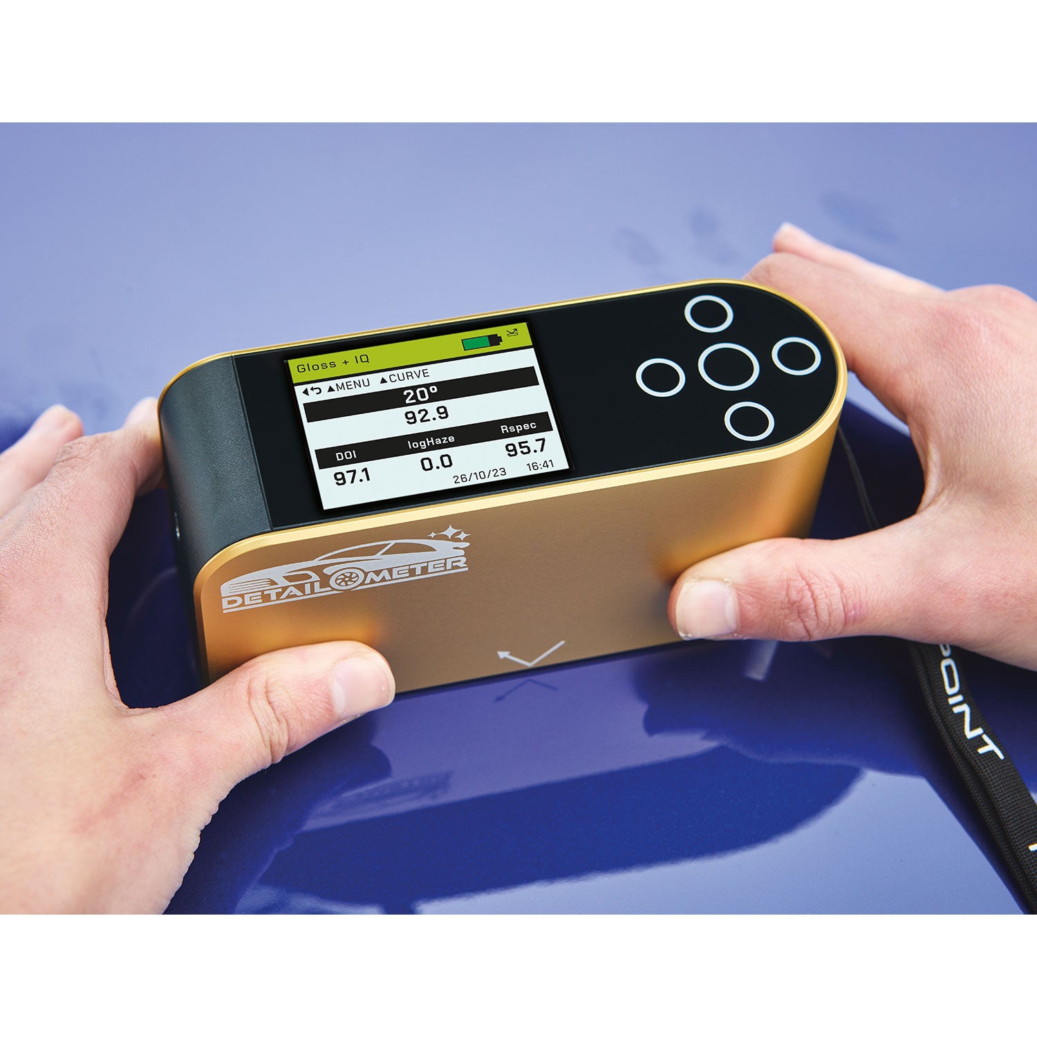 Person holding a detailometer on a blue car surface