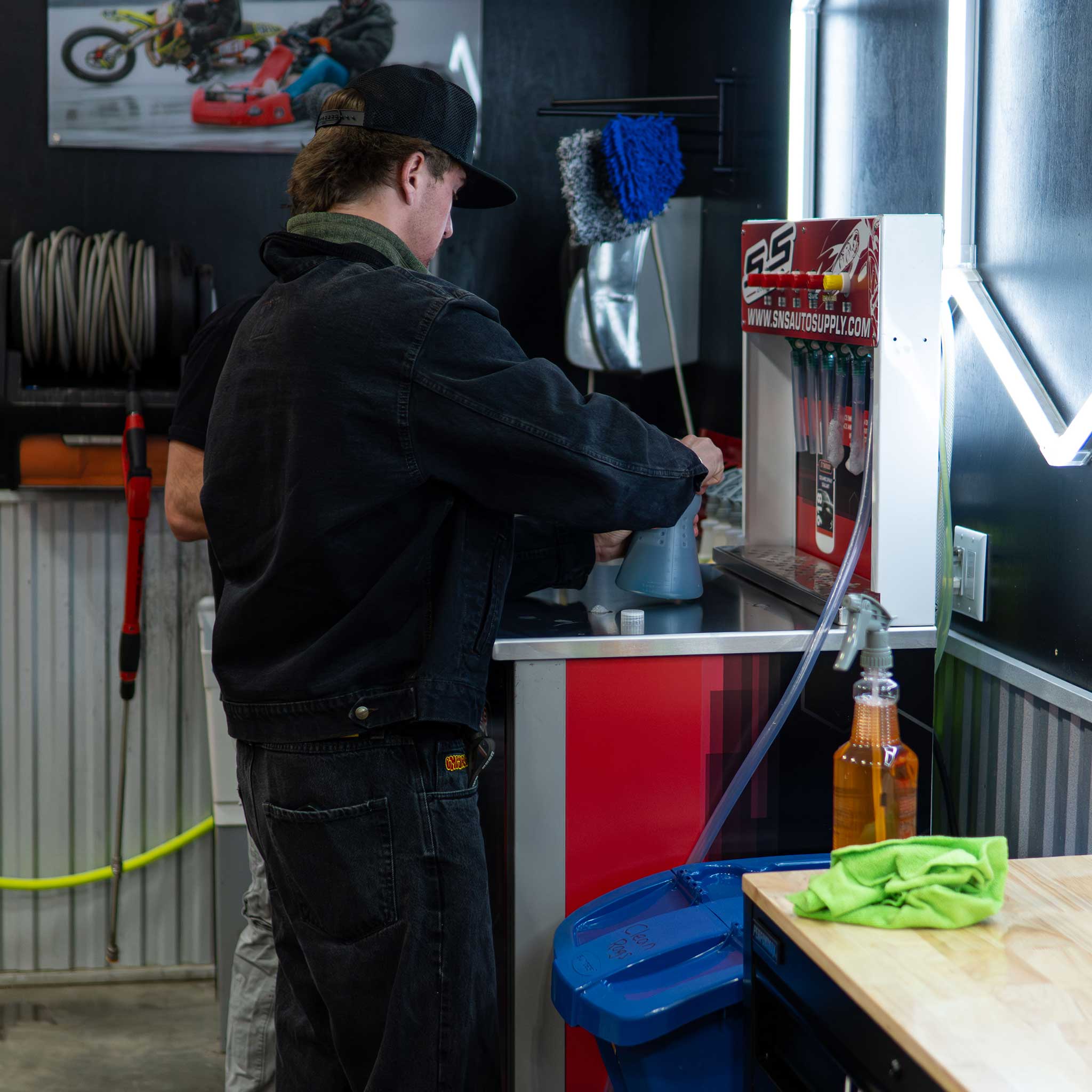 Person working on filling a foam cannon in a garage with tools and equipment around