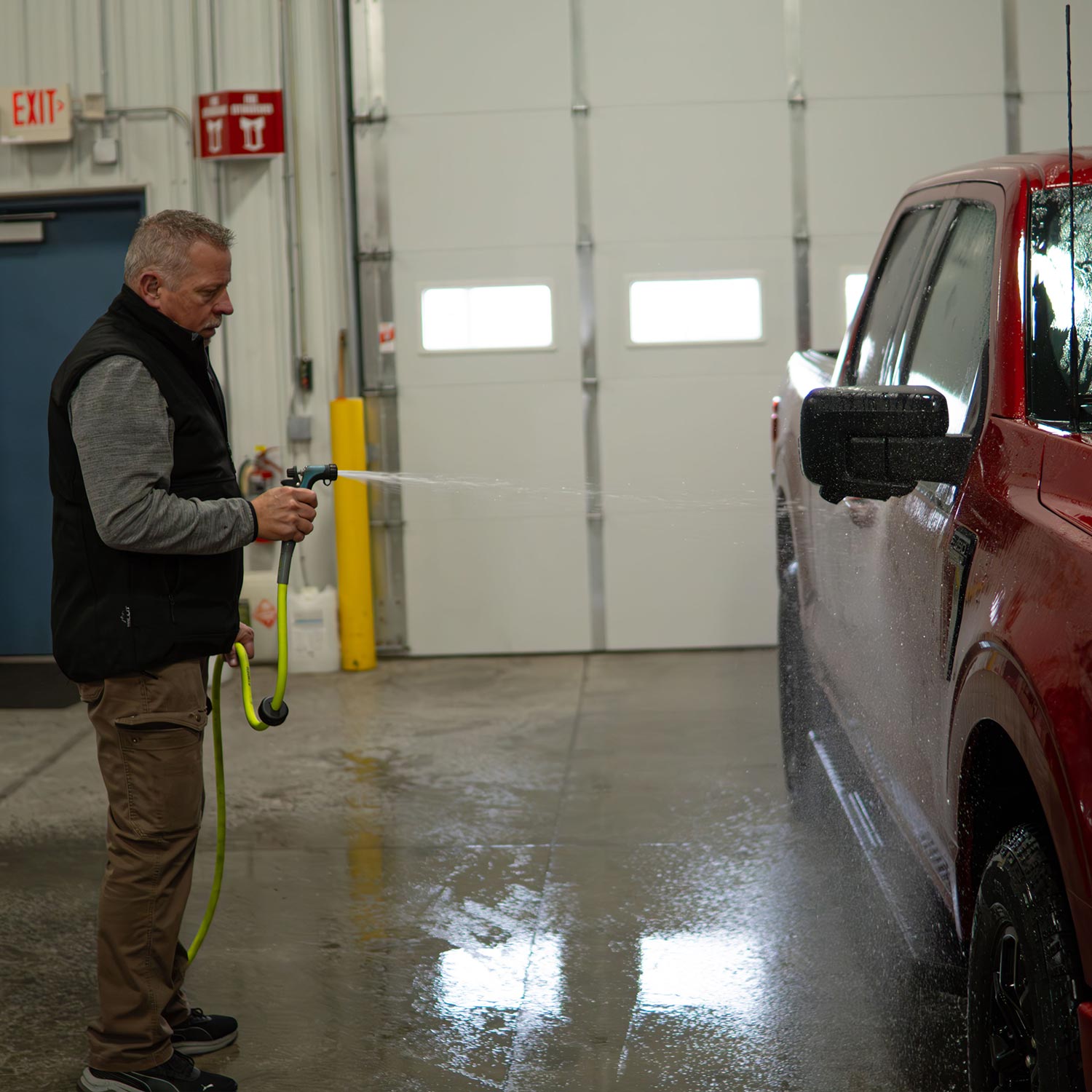 Garden hose water sprayer on a red pickup truck