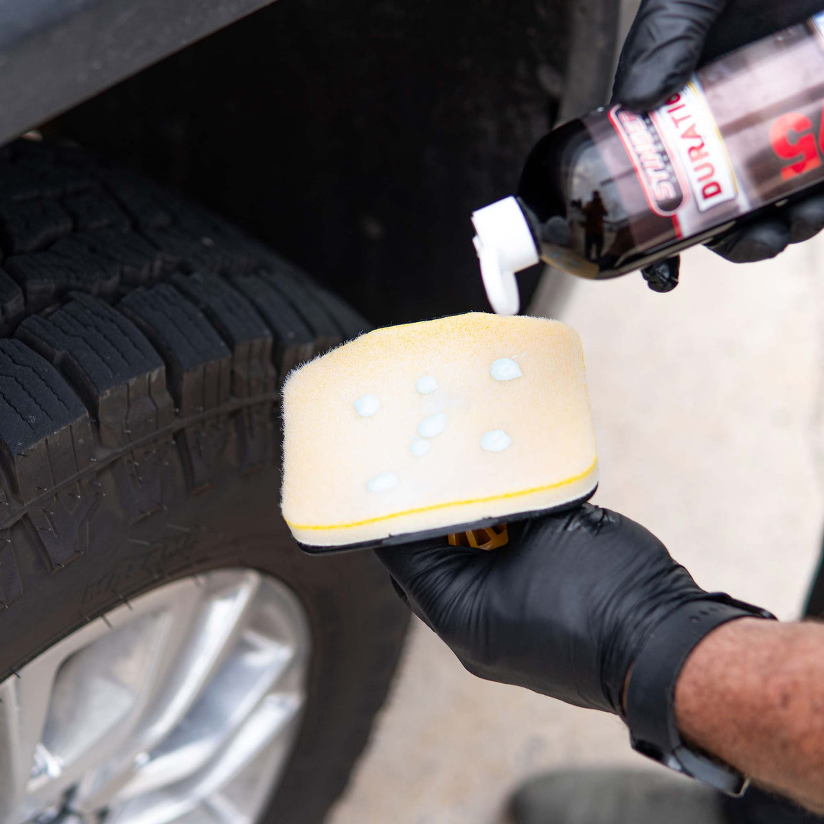 Hi-Tech 2250 tire applicator pad being loaded with Stinger Duration tire dressing