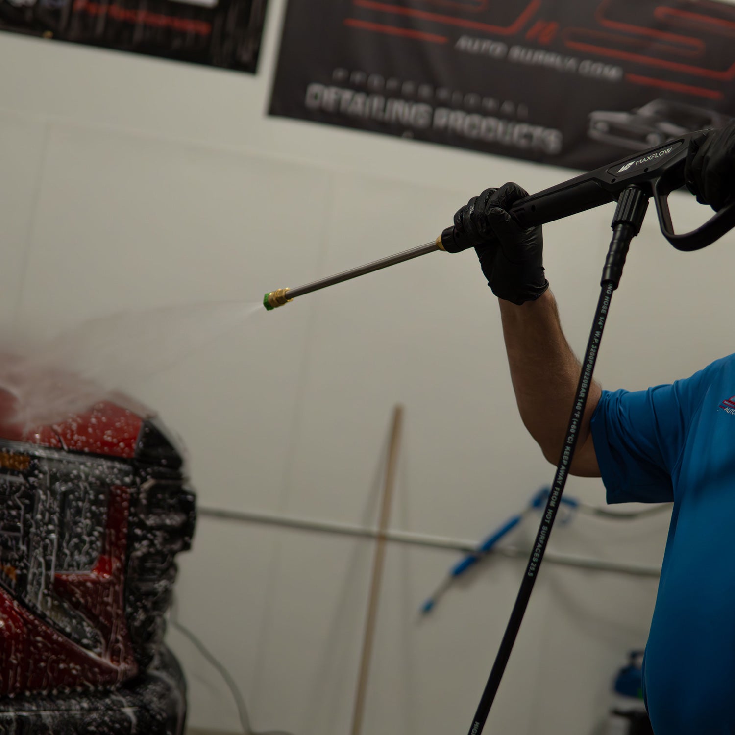 Person using a pressure washer on a car in a garage setting