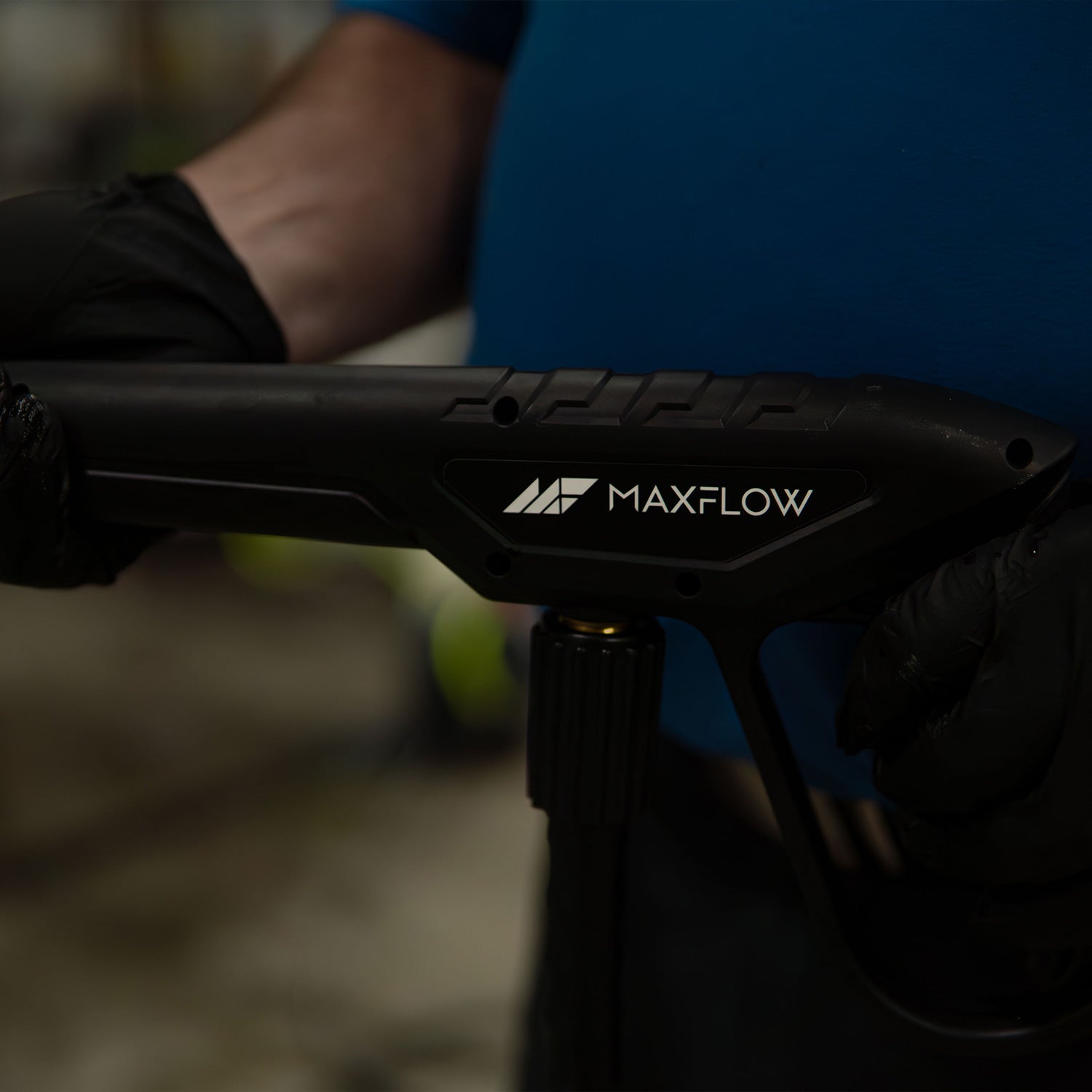 Black MAXFLOW spray gun held by a person with a blurred background