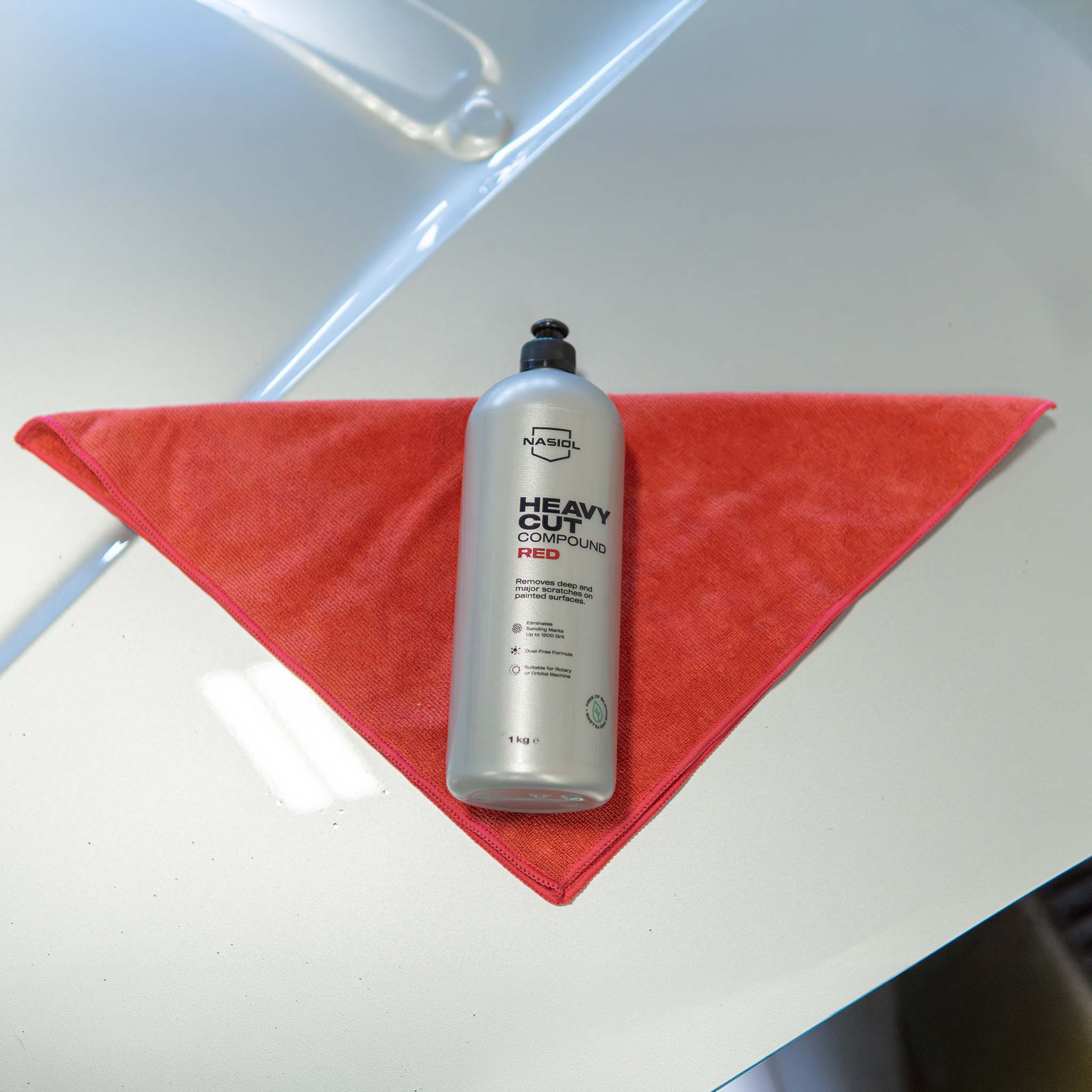 Bottle of 'Heavy Duty Compound Red' on a red towel with a blurred background