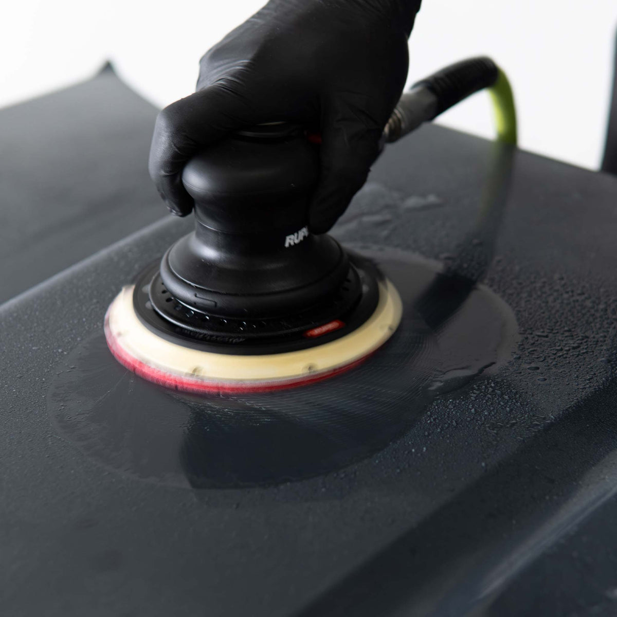 Wet sanding a black panel with a RUPES sander and a DryFinish foam disc