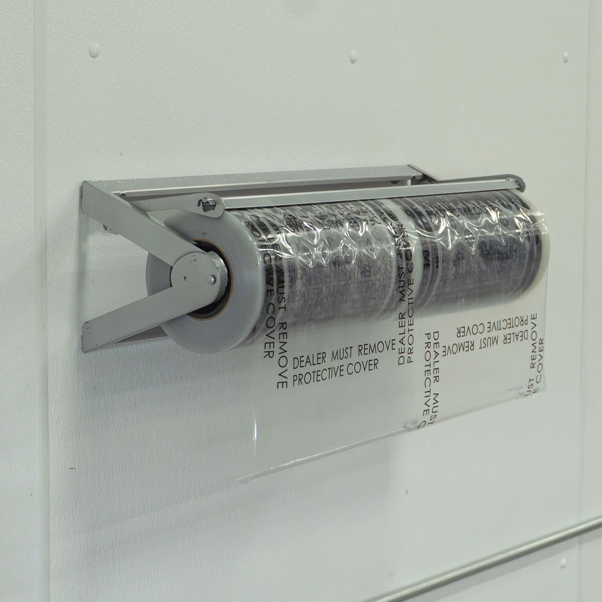 Stinger 600 foot carpet film roll loaded on a wall mounted dispenser with a cutting bar