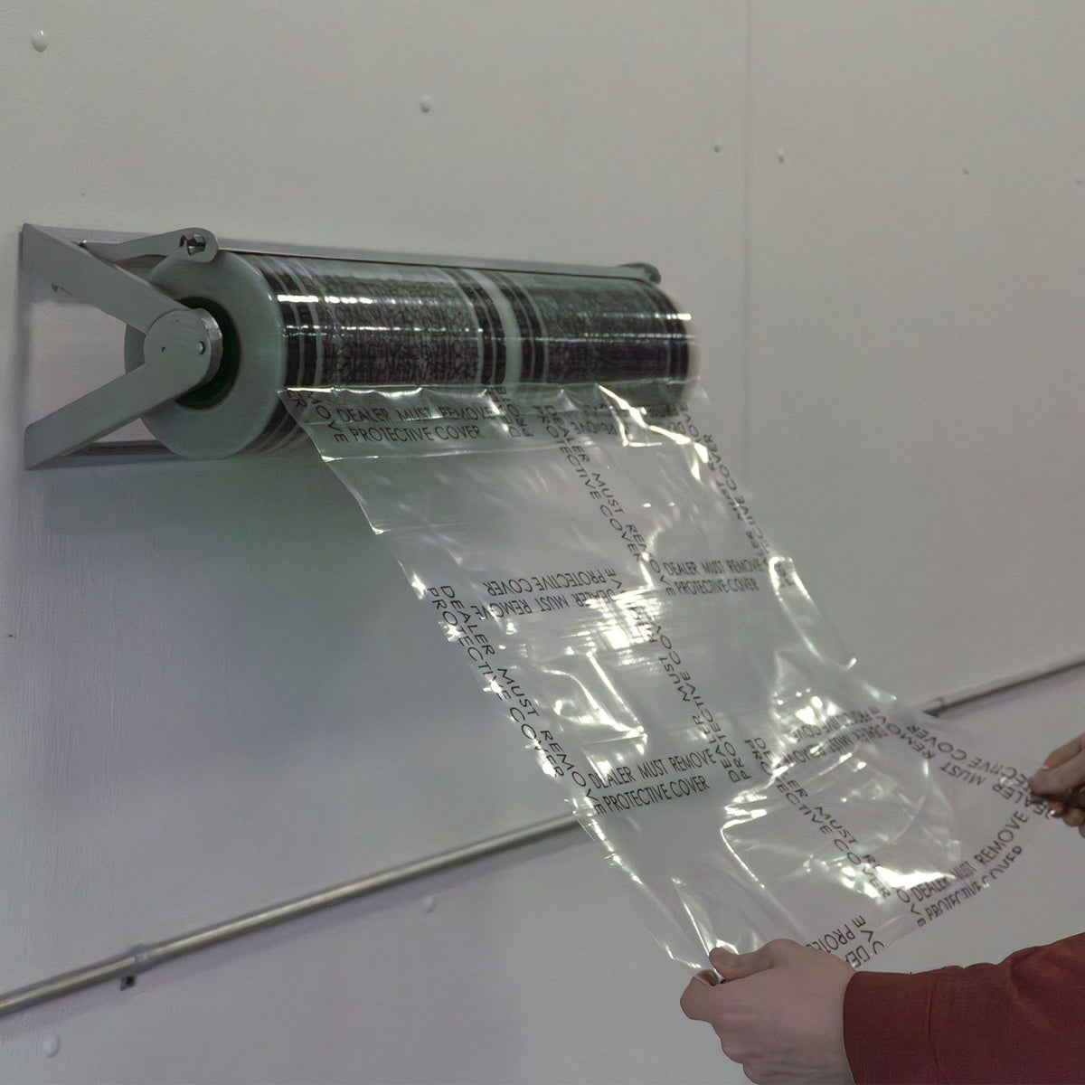 Pulling and tearing a sheet of carpet film from a wall mounted dispenser in a shop