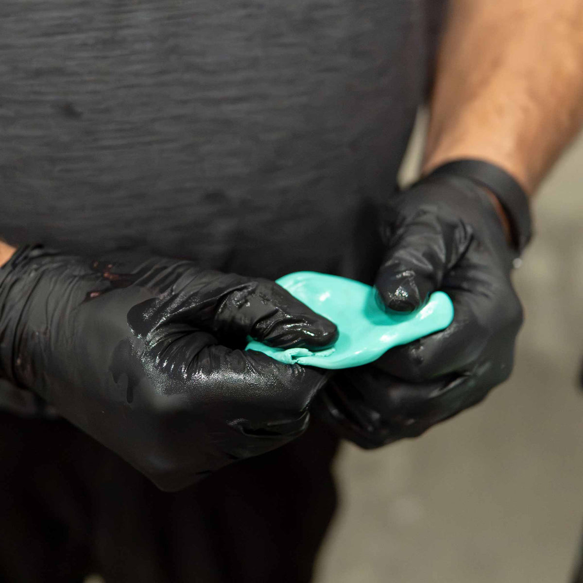 Gloved hands flattening a Stinger fine grade mint green clay bar into a working pad