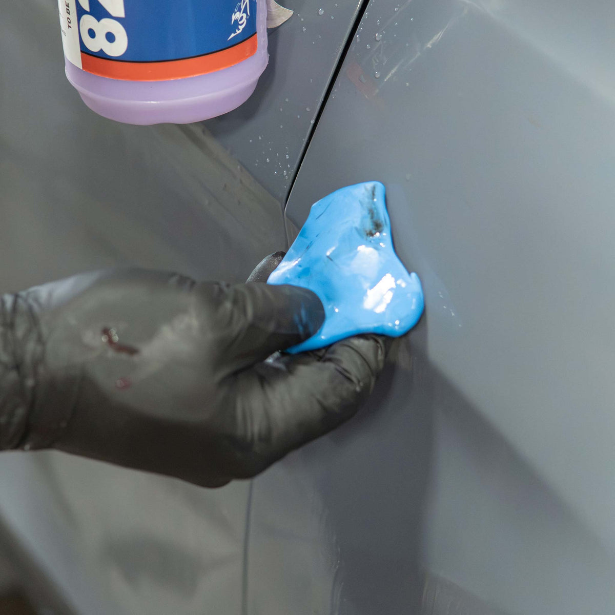 Stinger blue clay bar pulling rail dust and brake dust off a gray car fender