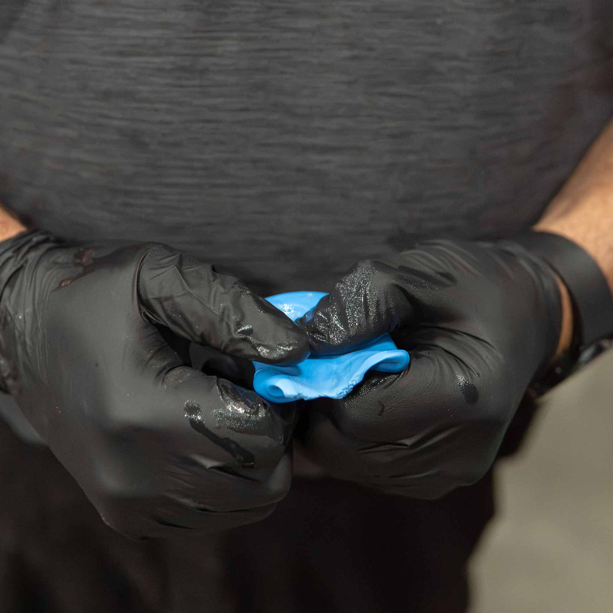 Gloved hands kneading a Stinger heavy duty blue clay bar flat before claying paint