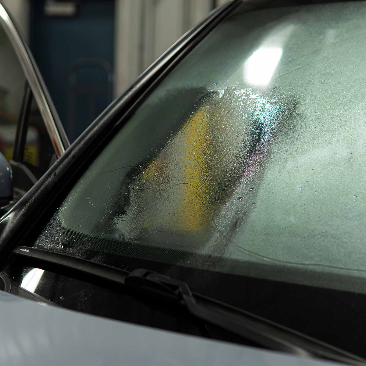 Windshield with a polished clear section beside hazy water spotted glass after rayon polishing
