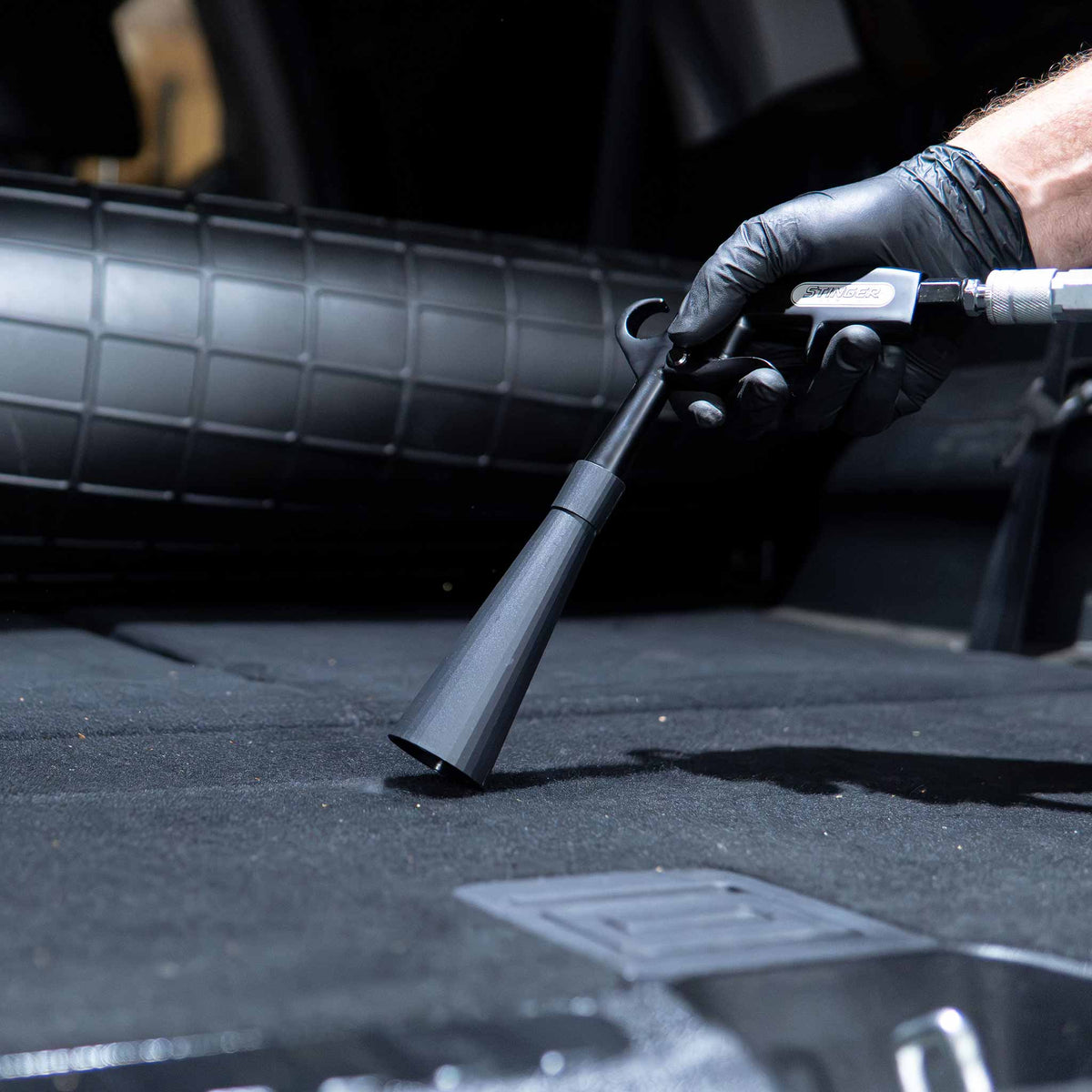 Stinger Twister Blow Gun vortex nozzle blowing dust from a carpeted trunk floor