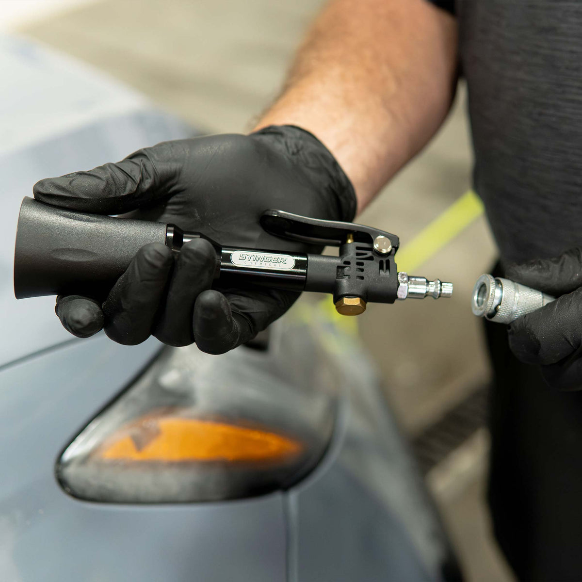 Stinger Twister Mini Blow Gun being connected to an air hose coupler over a car fender