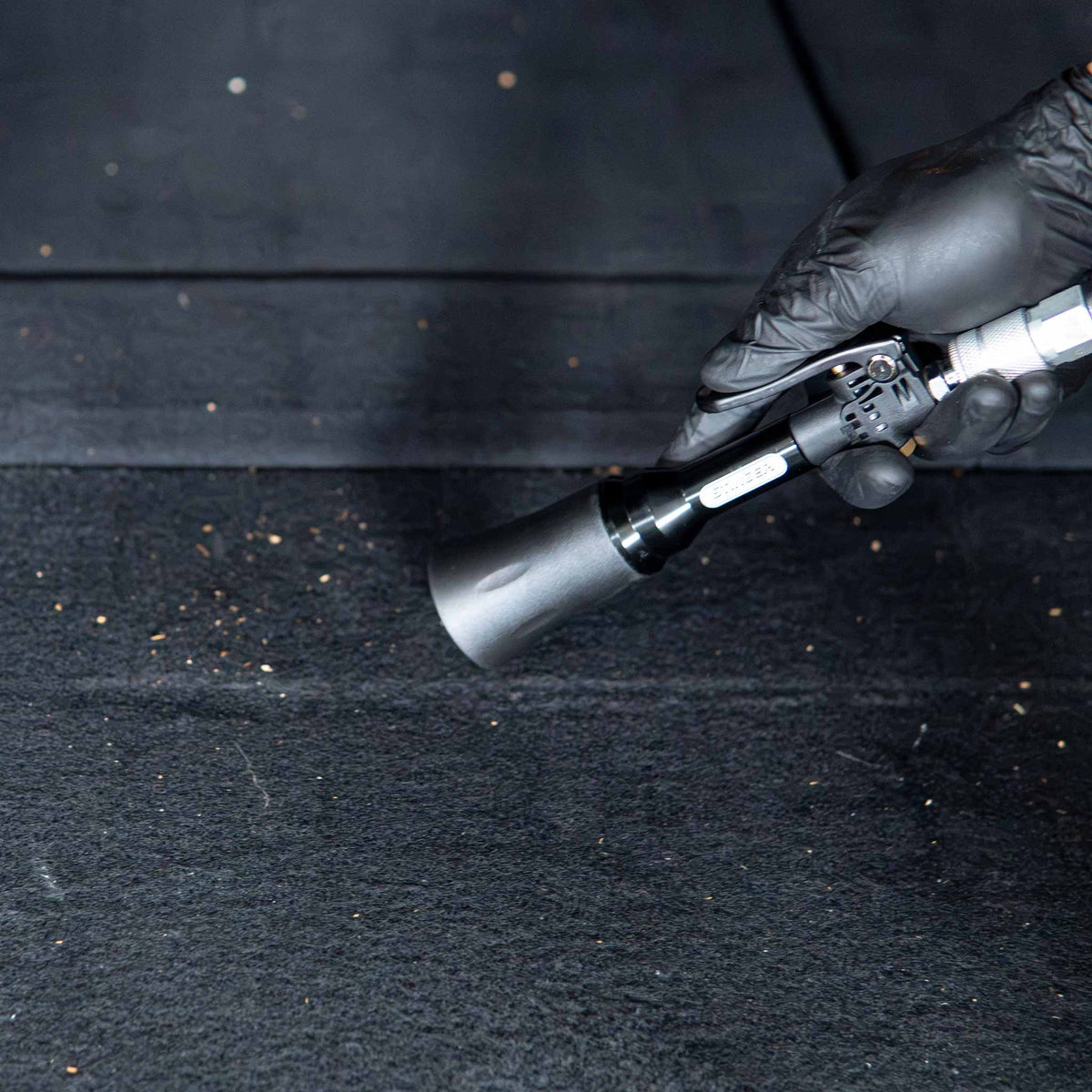 Stinger Twister Mini Blow Gun blowing debris off trunk carpet with its vortex nozzle