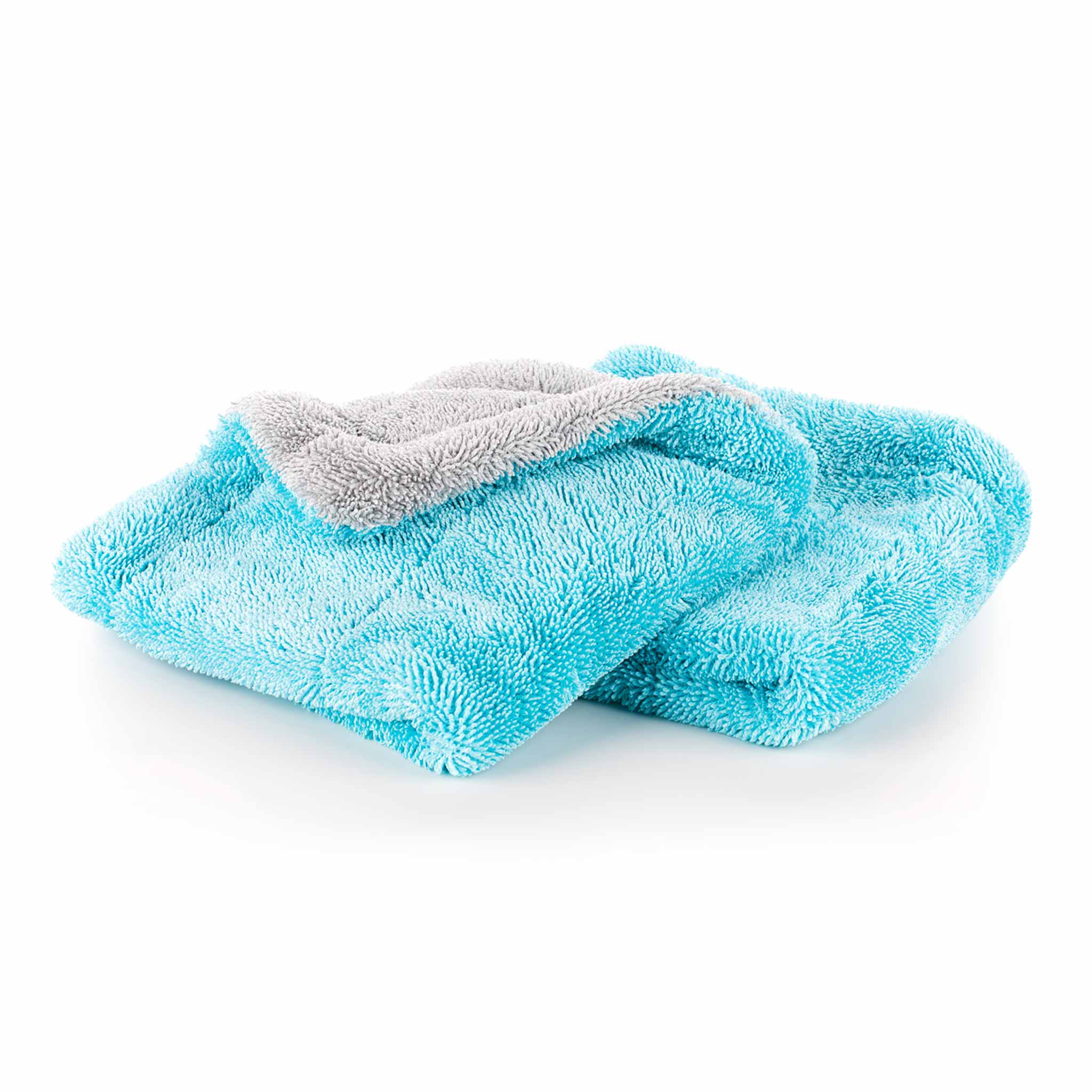 A folded plush drying towel in bright aqua blue with a contrasting light gray layer, shown on a clean white background.