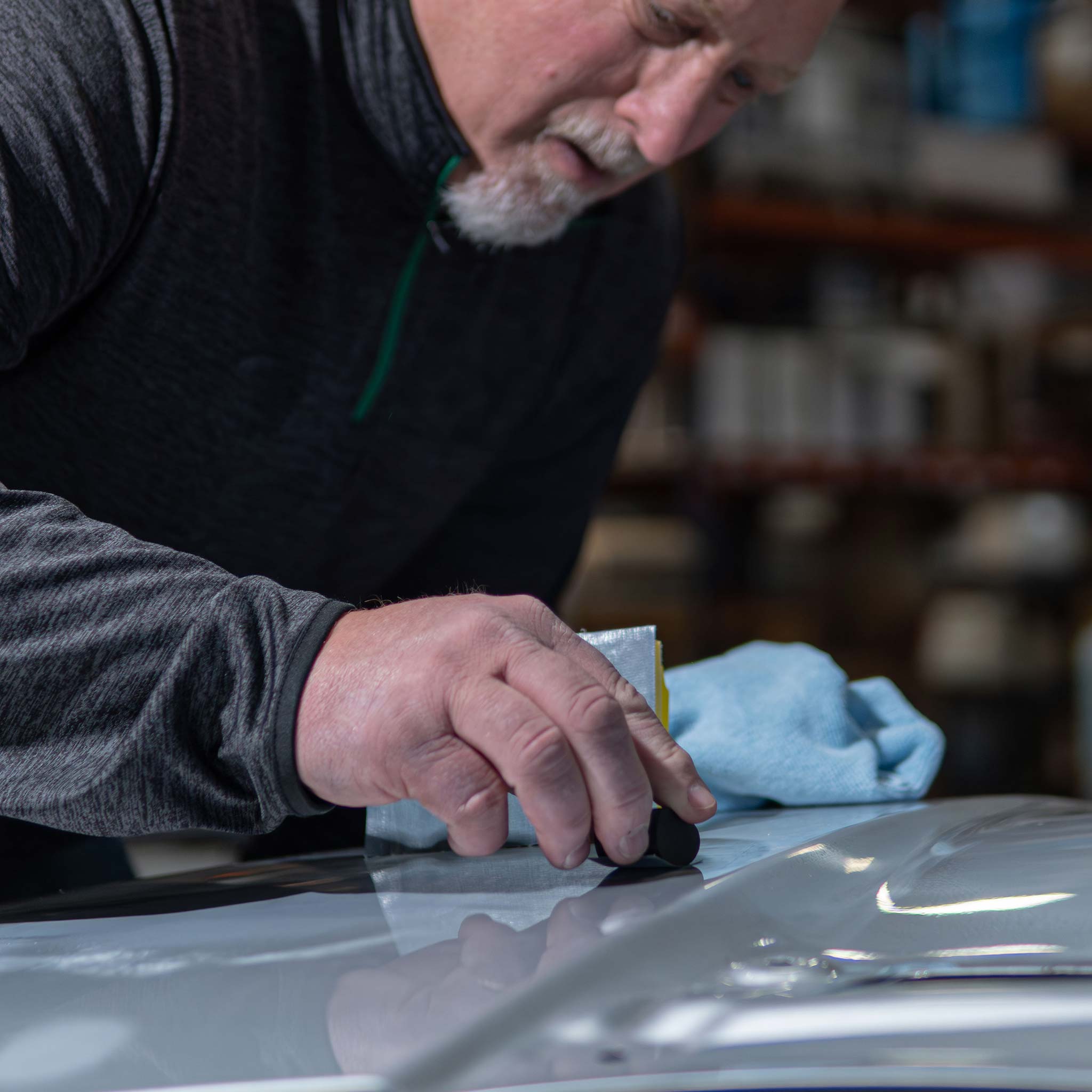 man using a tolecut sander on a car hood