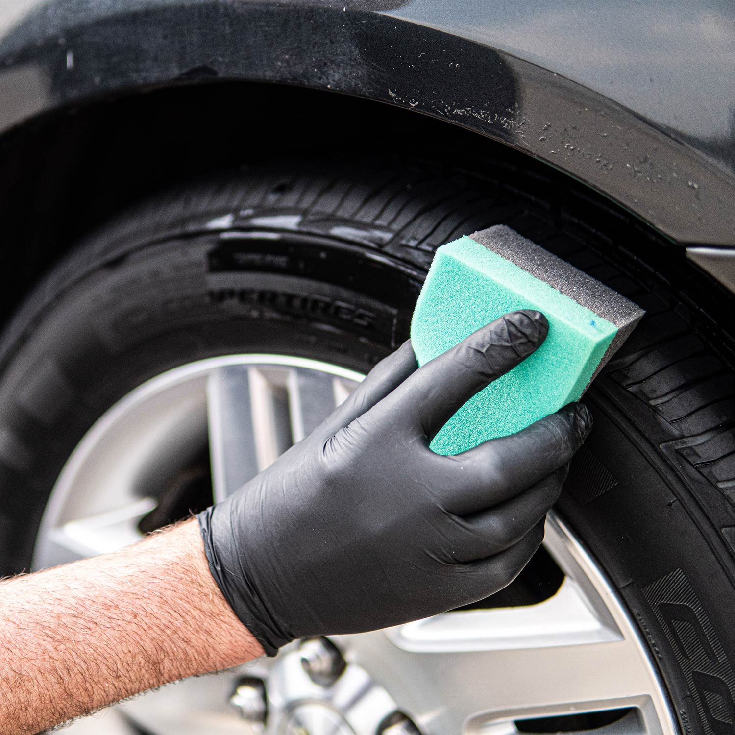 green-and-black-tire-dressing-applicator-in-use-on-tire